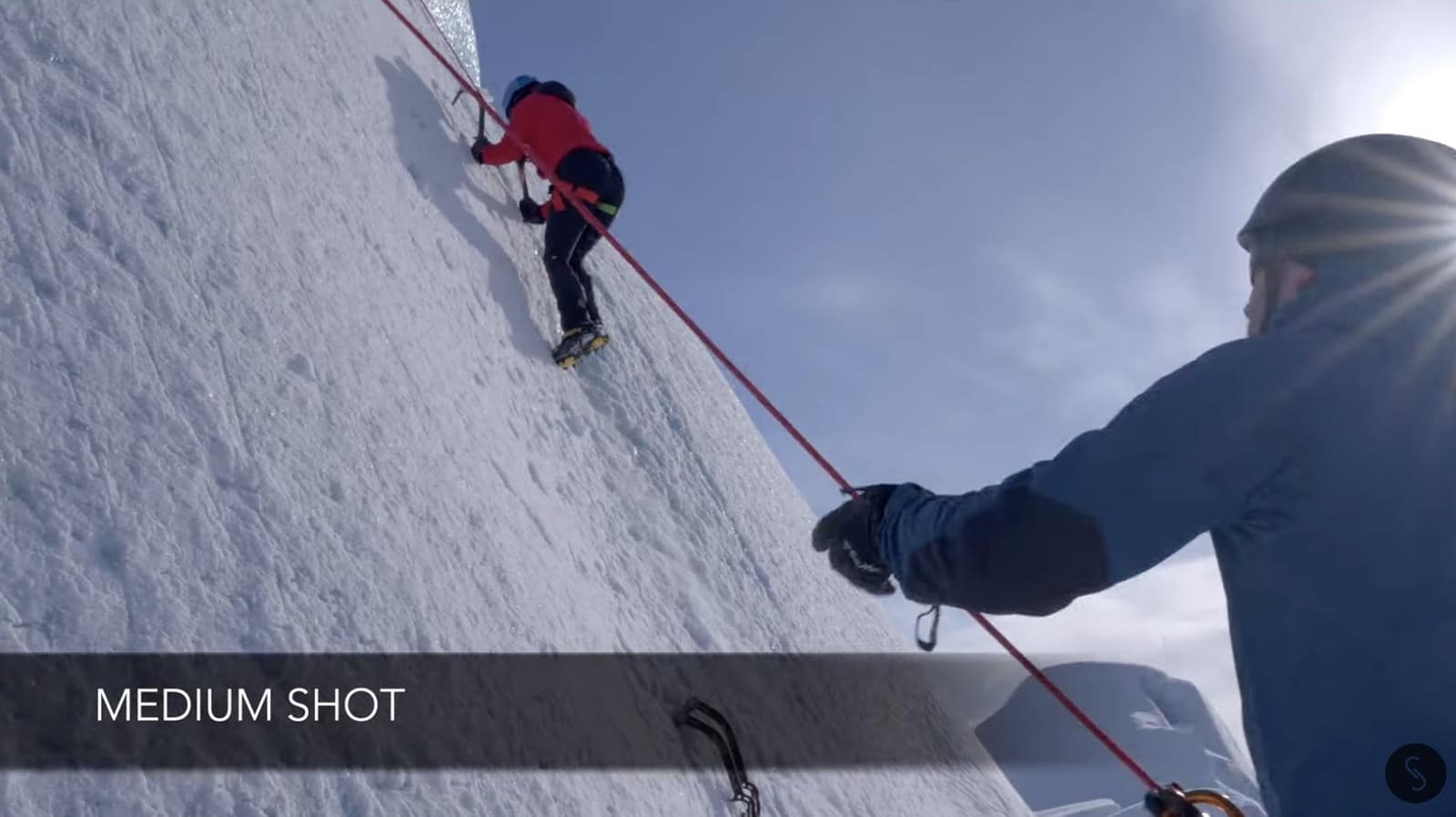 Ground-camera shot of a climber starting up the iceberg face.