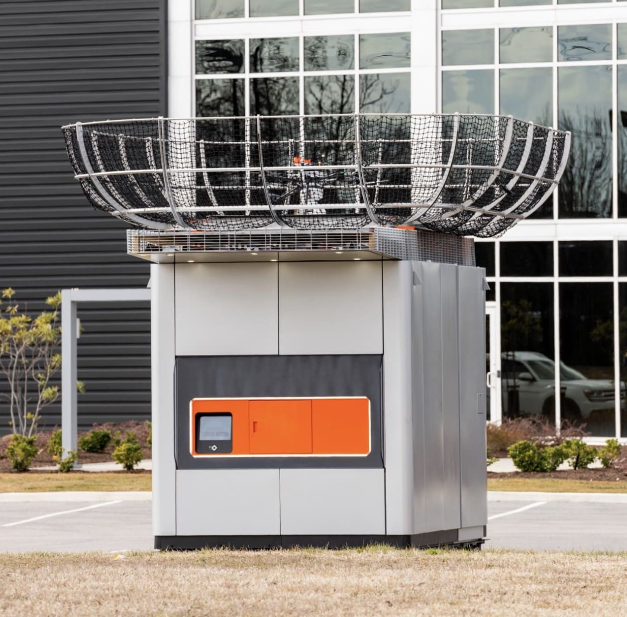 DroneUp automated ground station with a mesh landing basket outside an office building.
