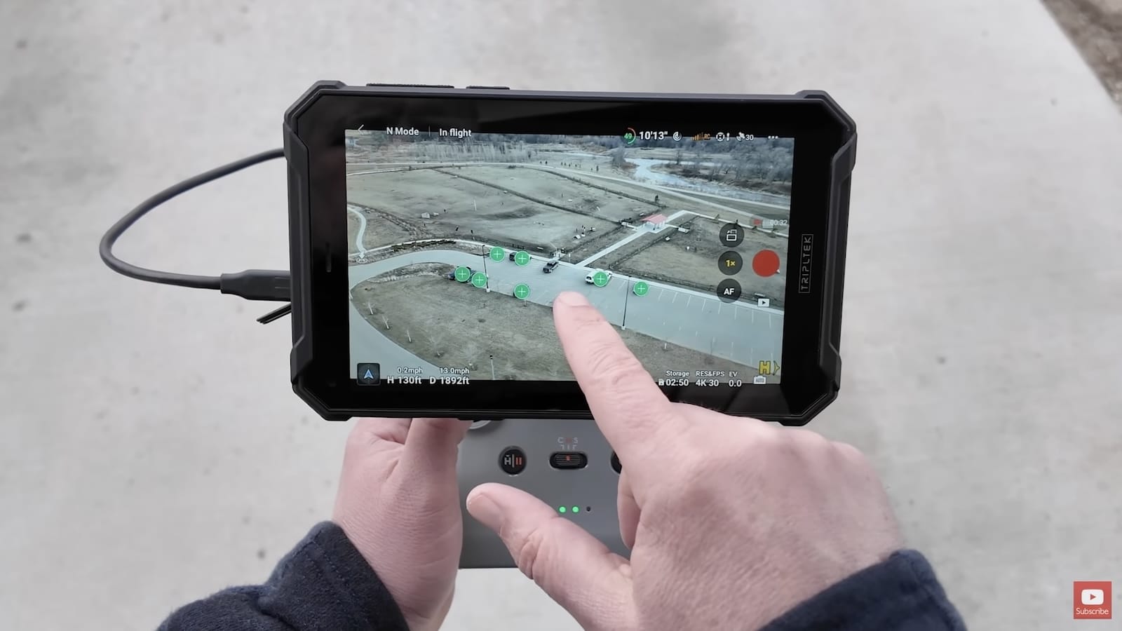 A finger taps a tablet controller screen to select a scanned tracking subject.