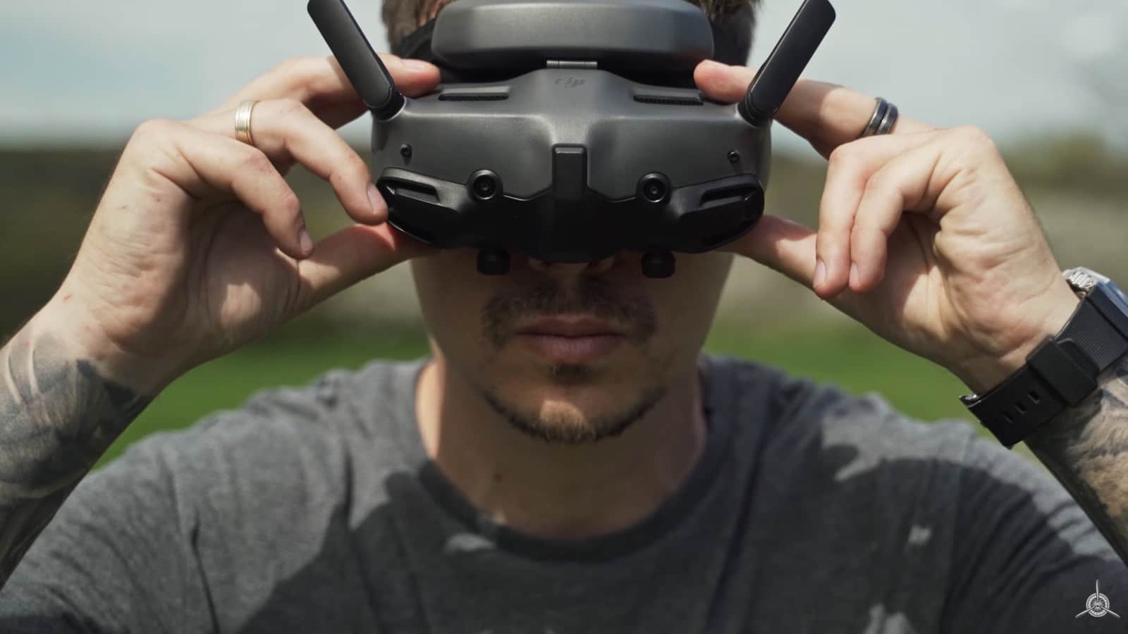 Person pulls DJI FPV goggles over their eyes in an open field.