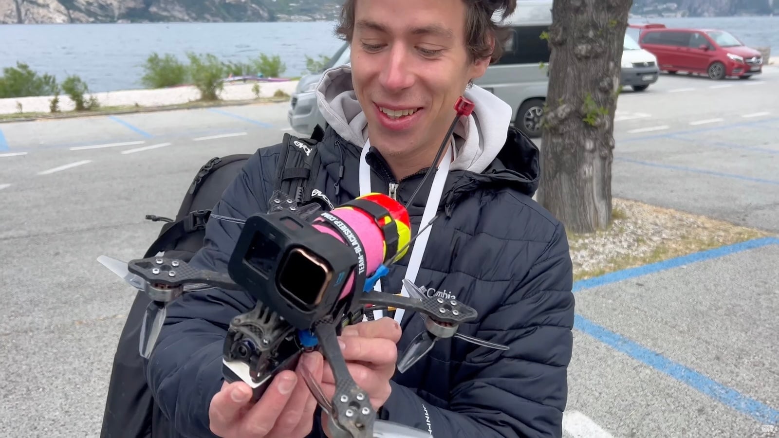 Windsurf foiler carving across Lake Garda as an FPV drone chases alongside.