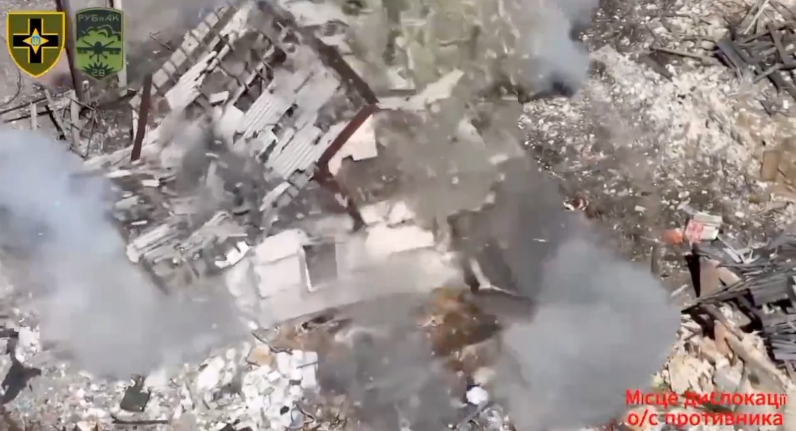 Drone footage of a building collapsing into smoke and dust after a strike.