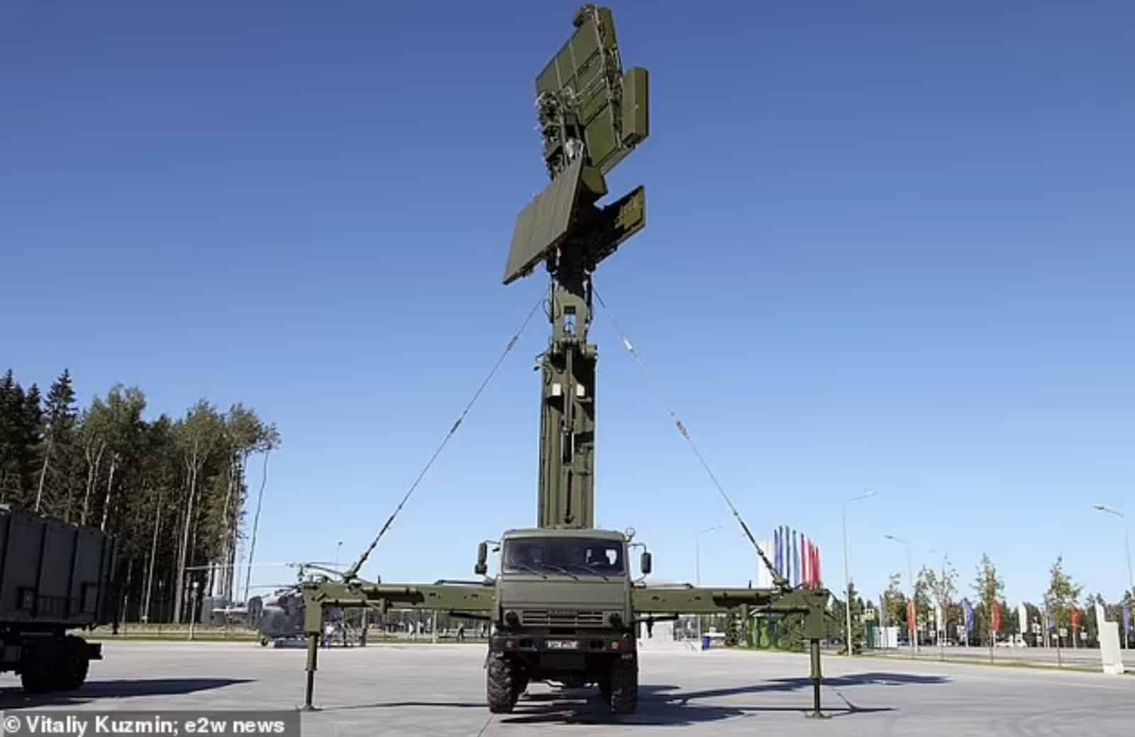 A truck-mounted Russian Podlyot radar with its antenna array raised on a paved lot.