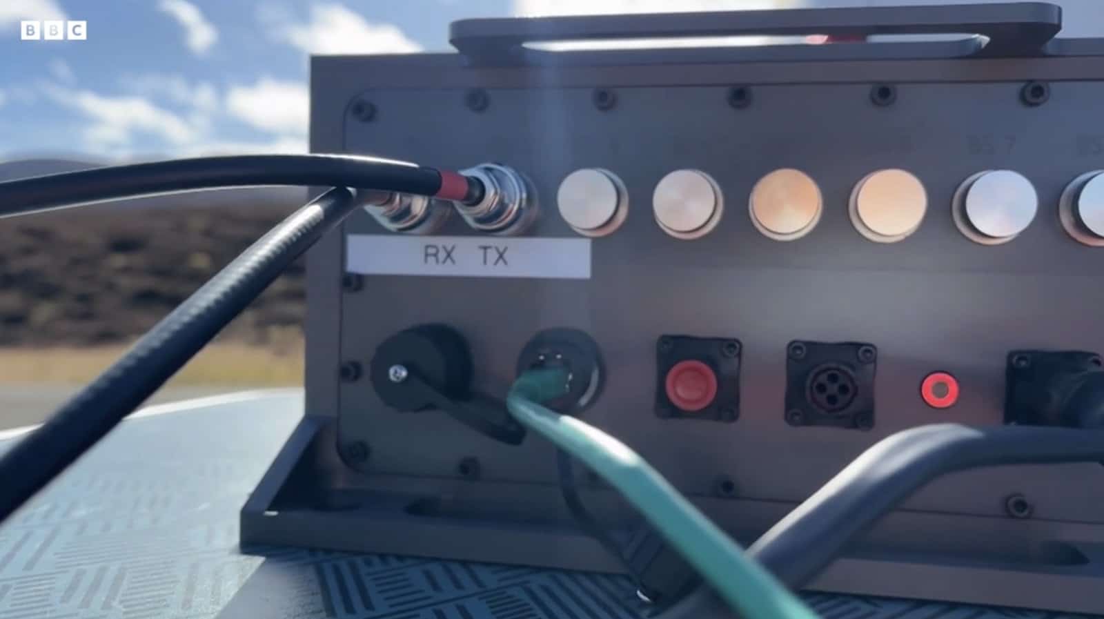 Portable 5G base station with labeled RX and TX ports wired up outdoors.