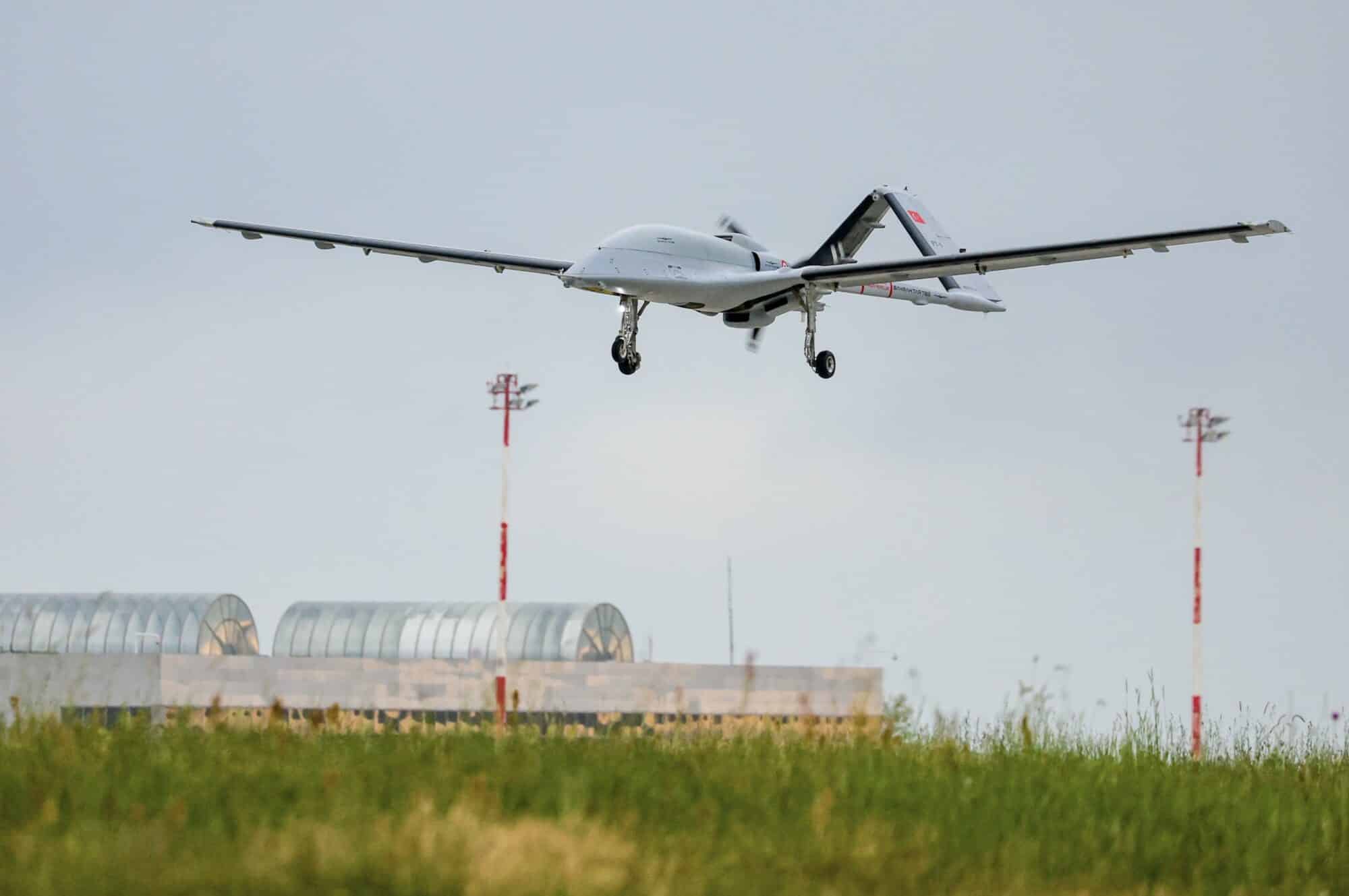 Bayraktar TB3 on approach with landing gear down over an airfield.