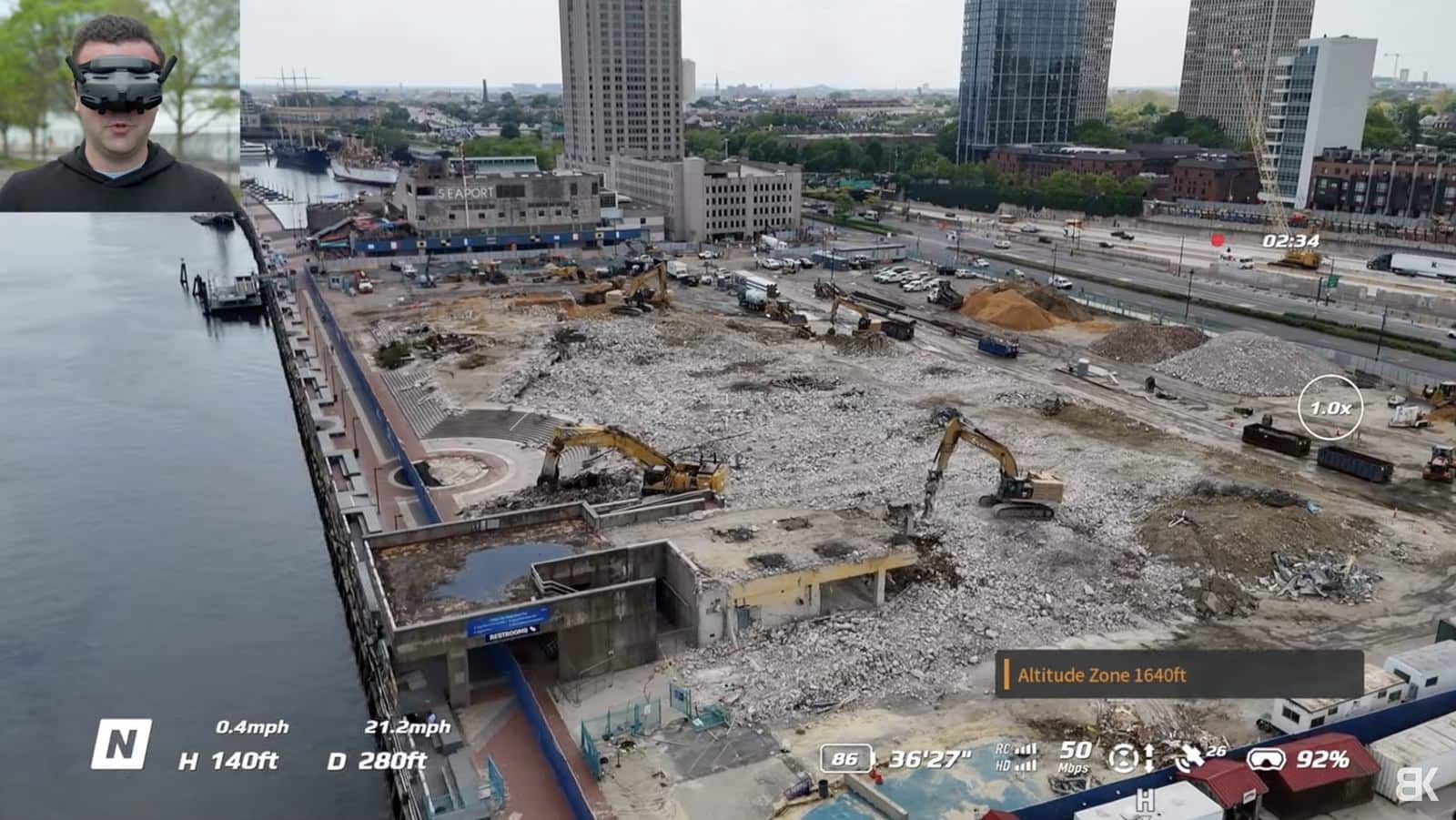 Goggles view of a waterfront demolition site with excavators and the city skyline.