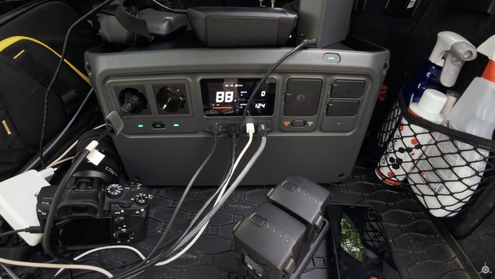 DJI Power 1000 station in a car trunk charging a camera and drone batteries.