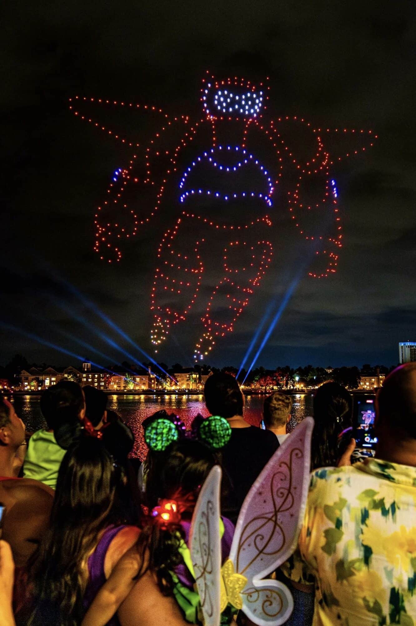Buzz Lightyear outlined in red and blue drones above a crowd with fairy wings.