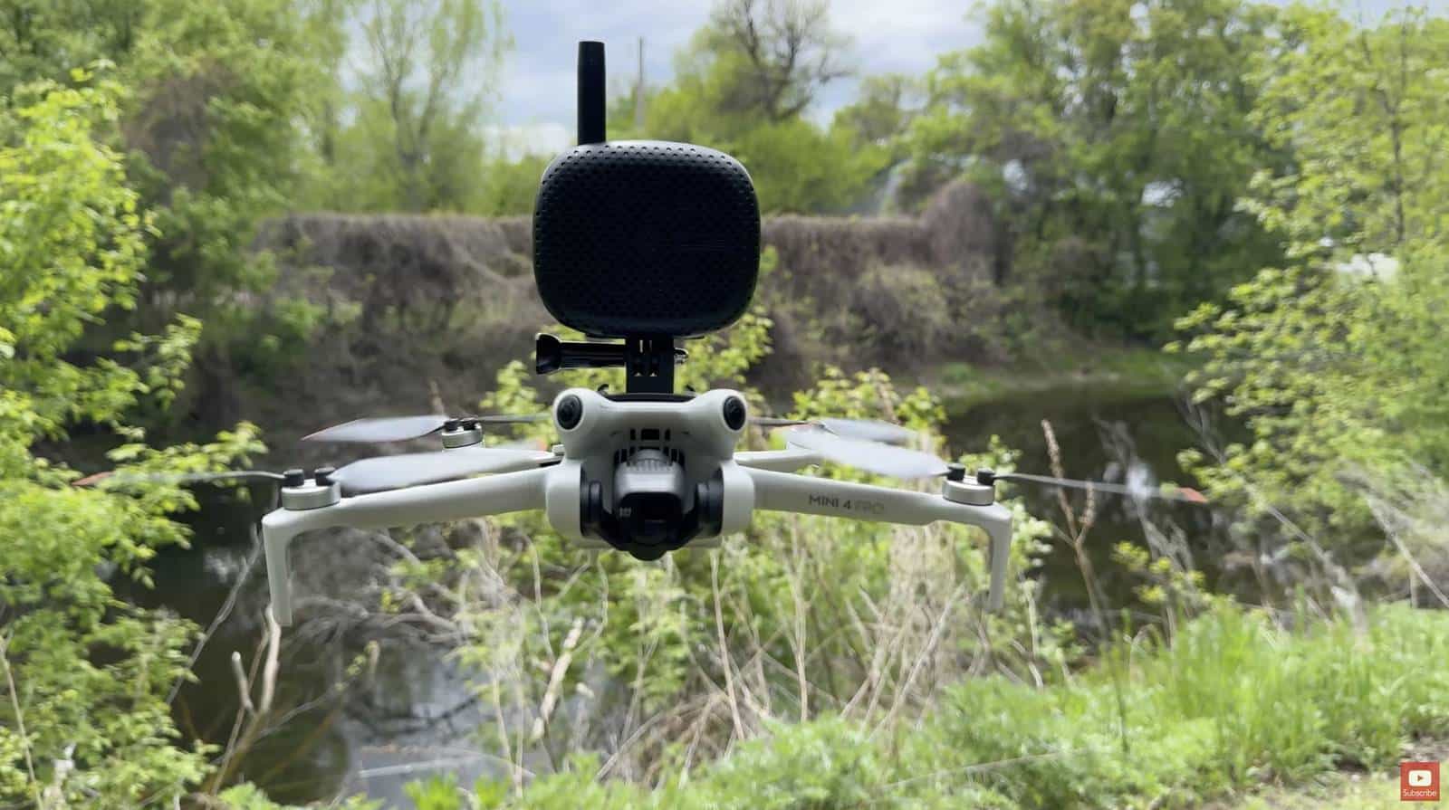 DJI Mini 4 Pro hovering over a creek with a speaker on a GoPro mount.