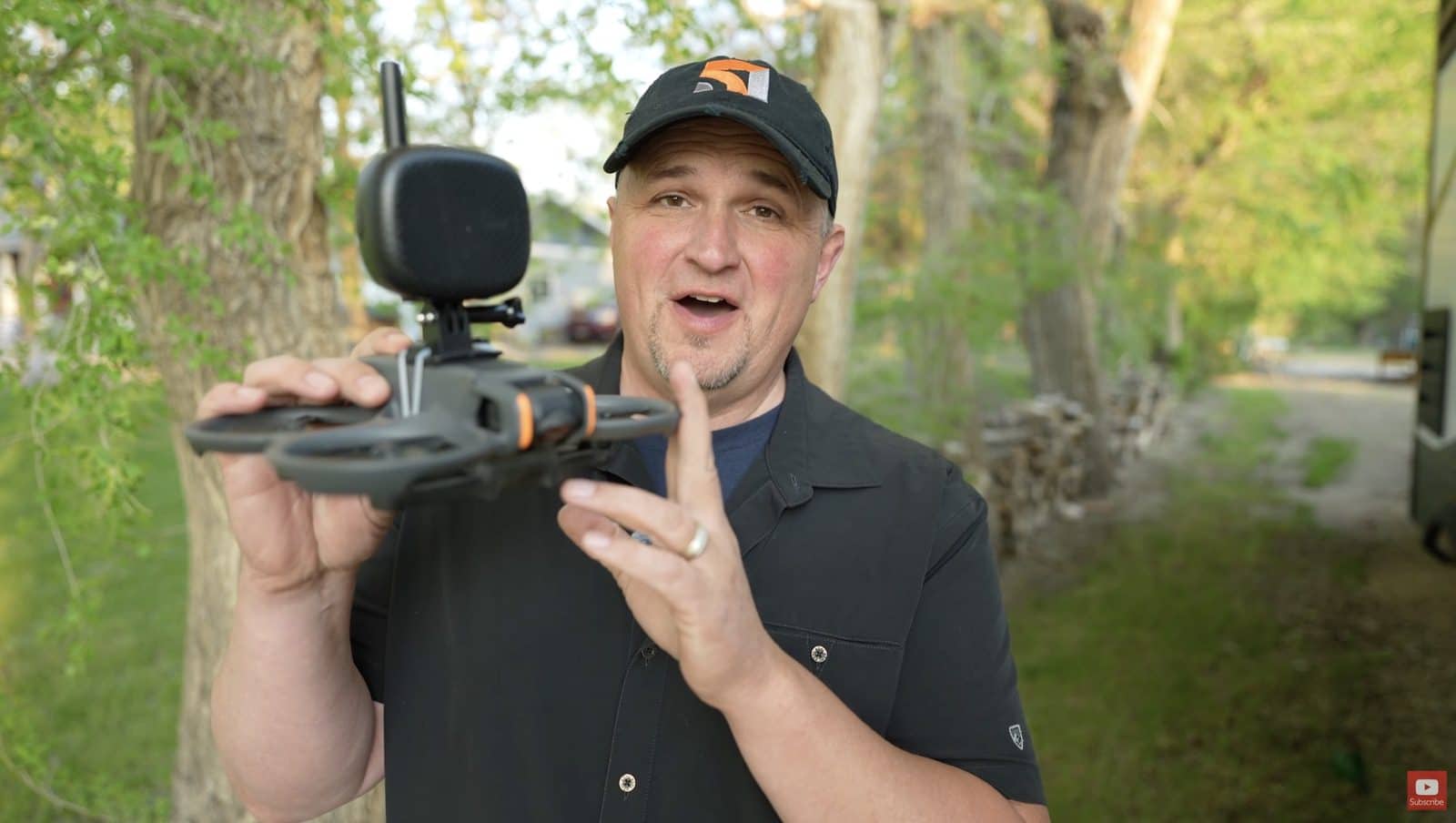 Reviewer holding a DJI Avata 2 outdoors with the speaker strapped to its top.