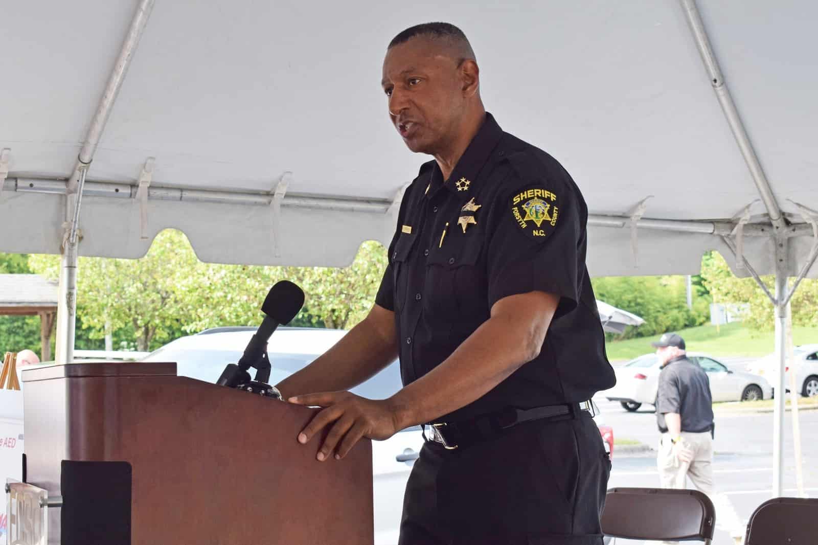 Forsyth County Sheriff Bobby Kimbrough Jr. speaking at a lectern under a tent.