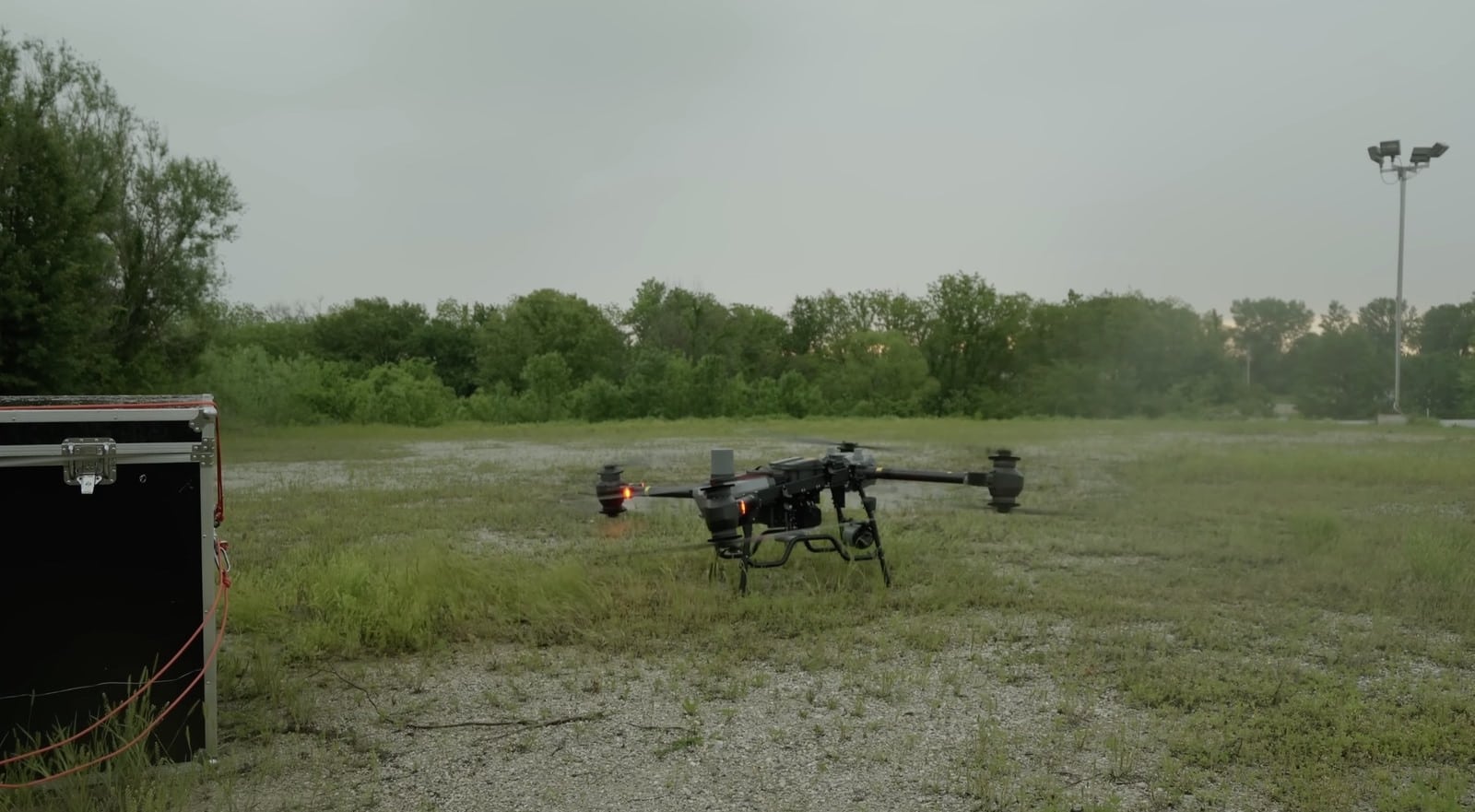 FlyCart 30 sitting on soggy grass next to a black equipment case.