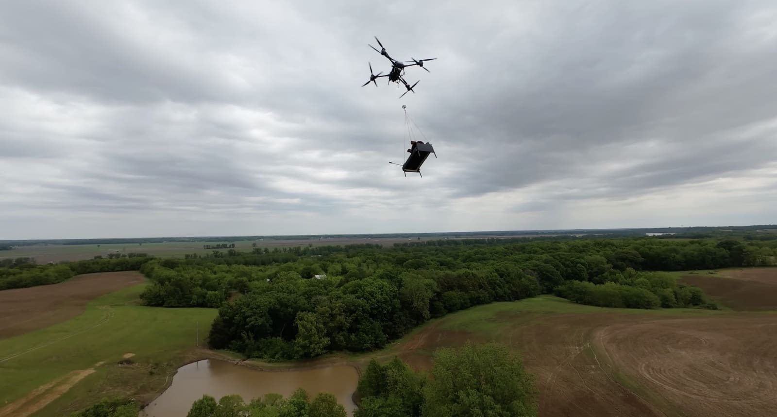 FlyCart 30 carrying a slung load high above Missouri farmland and a pond.