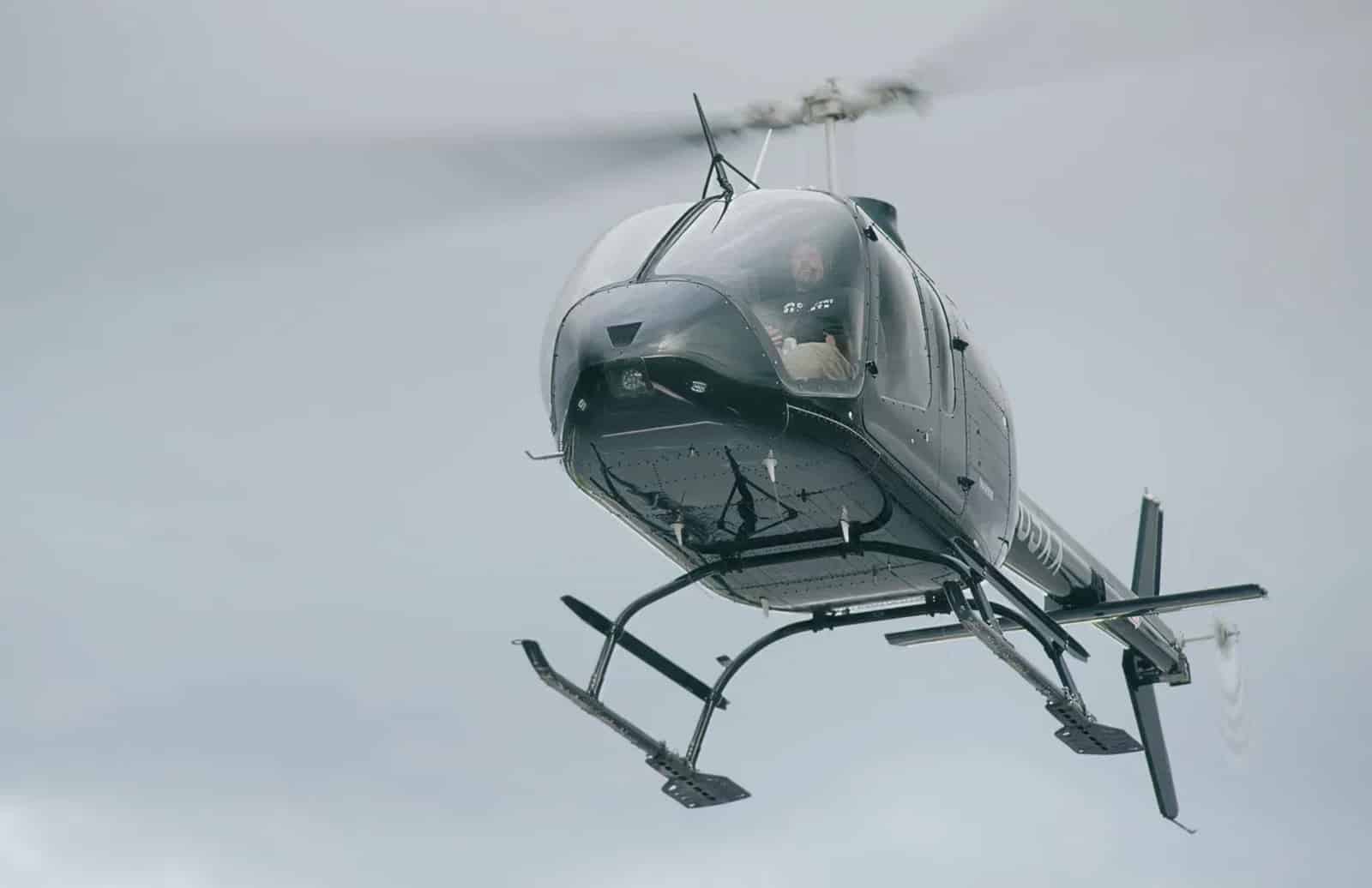 Black helicopter banking through overcast Utah skies during the vertiport demonstration.