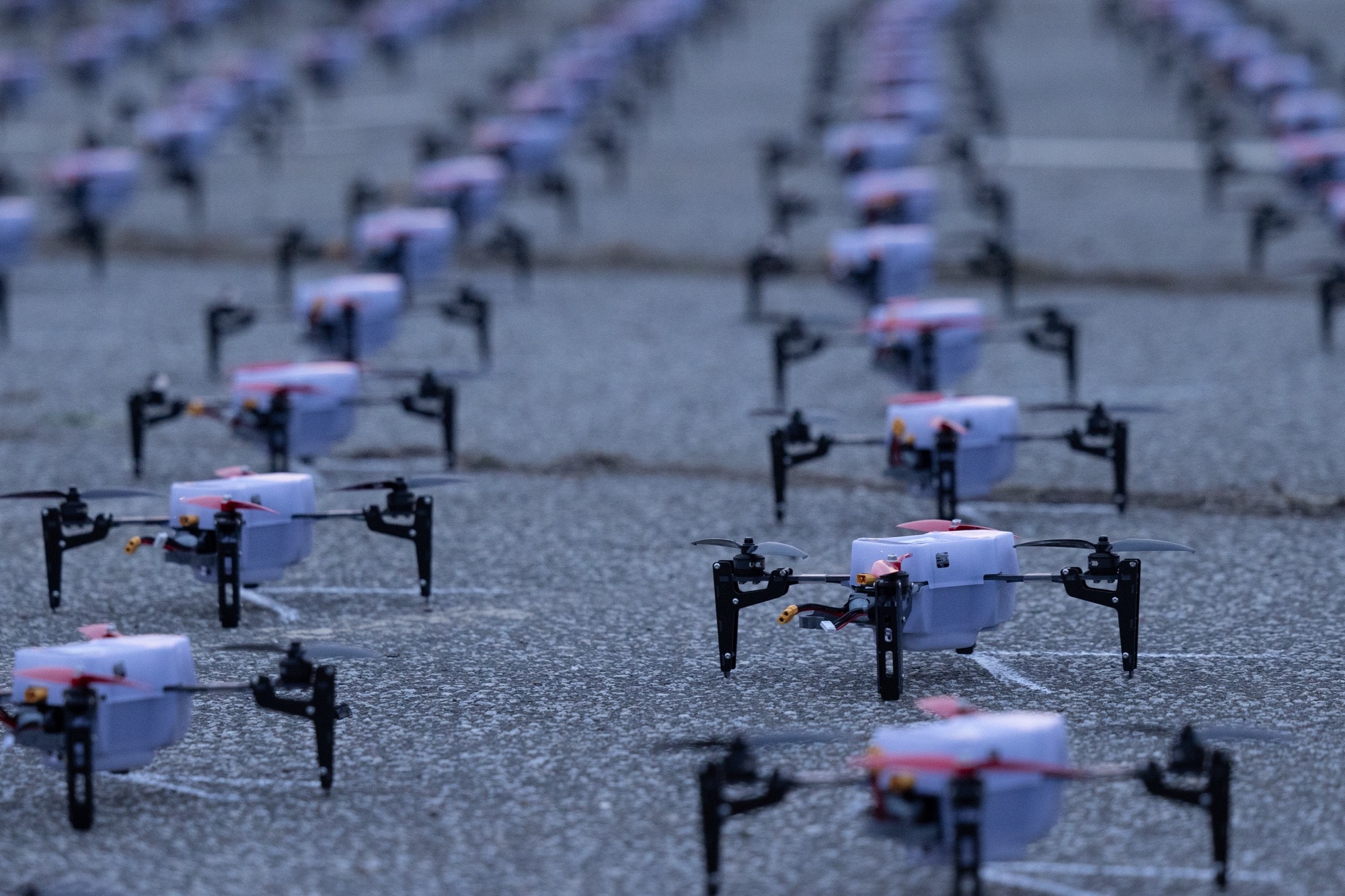 Hundreds of UVify IFO drones lined up in rows on pavement before launch.
