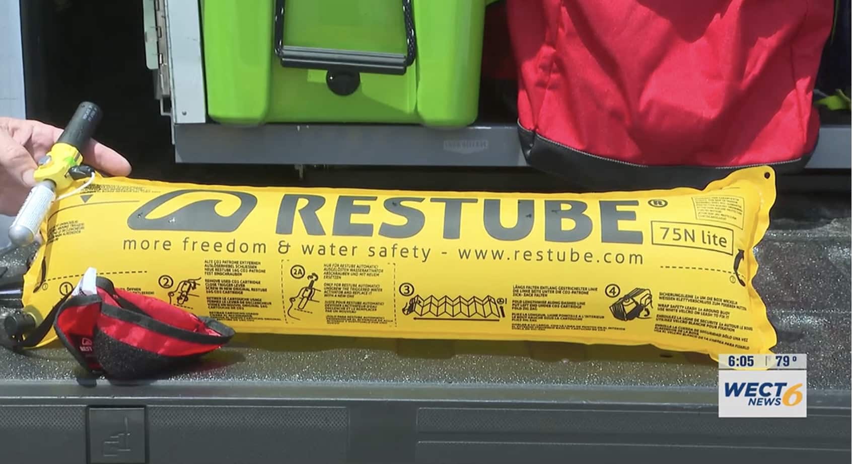 Hand holding a yellow Restube float and red pack beside the drone case.