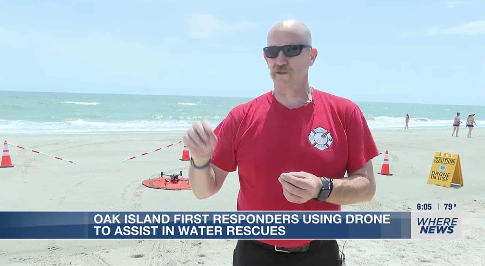 Oak Island firefighter in a red shirt talking beside a drone in a coned launch zone.