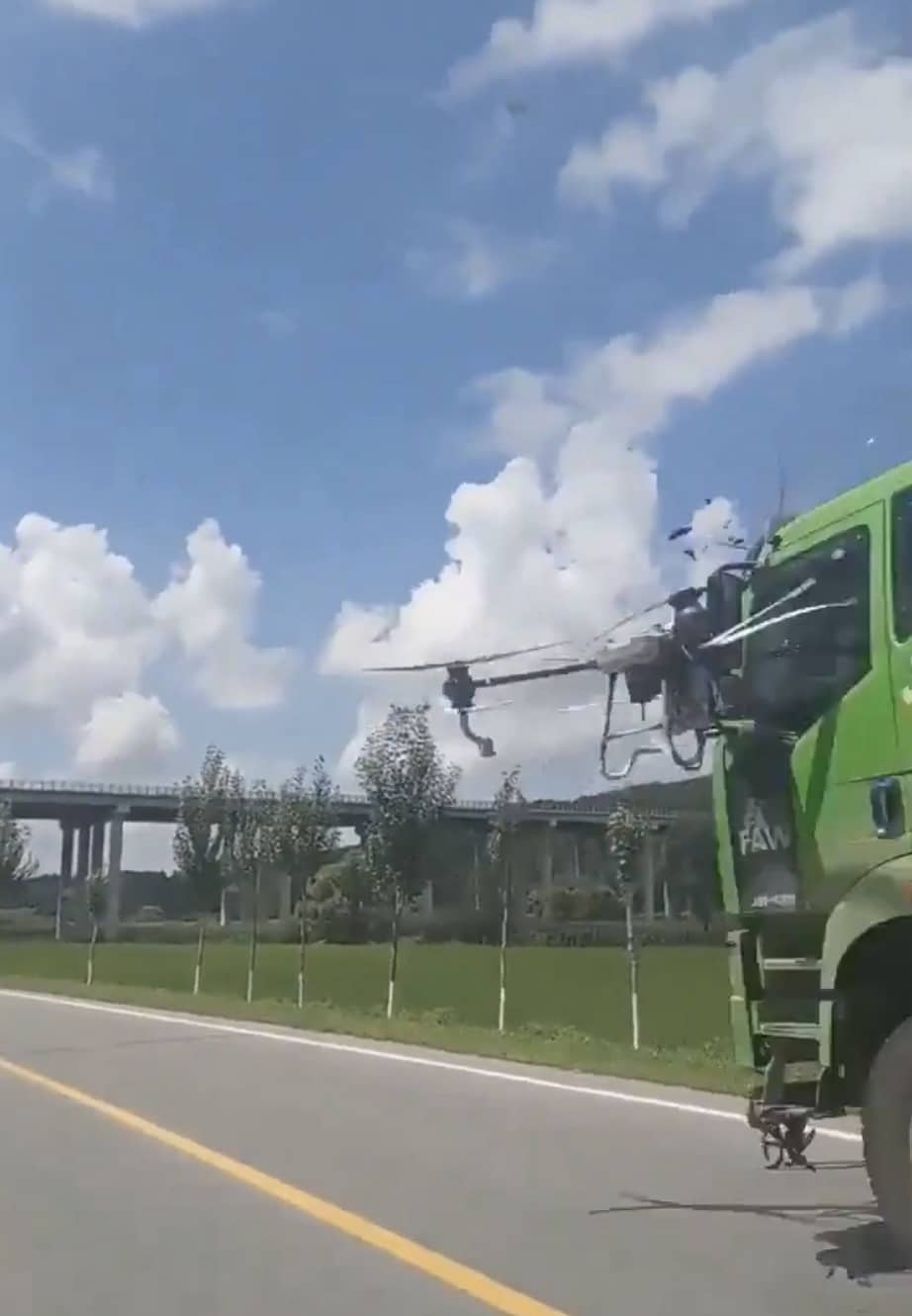 The spray drone closing on the cab of a green dump truck.