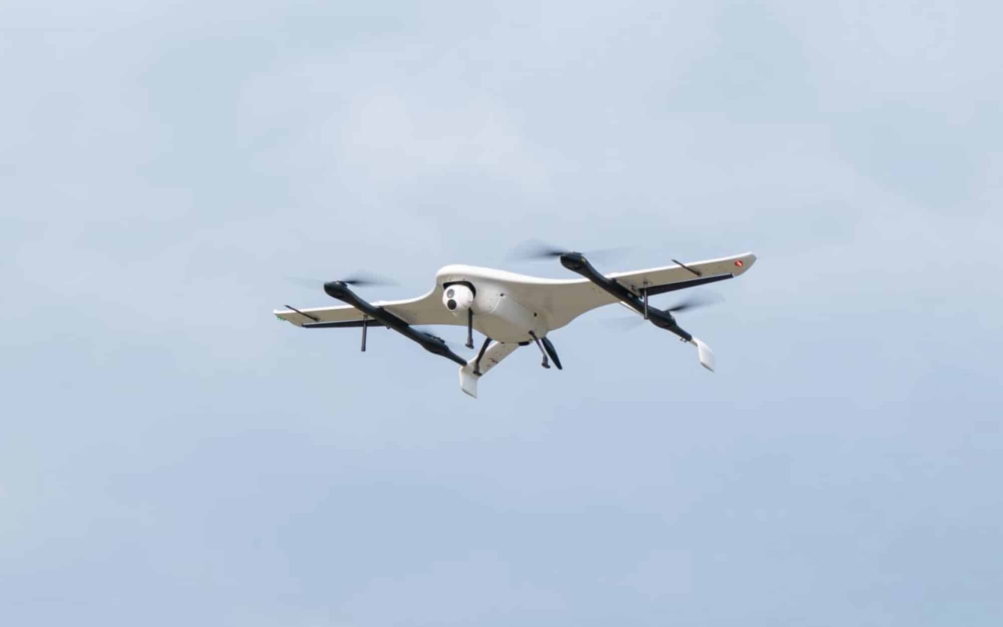 JOUAV CW-15V fixed-wing VTOL drone in flight with its lift rotors turning.