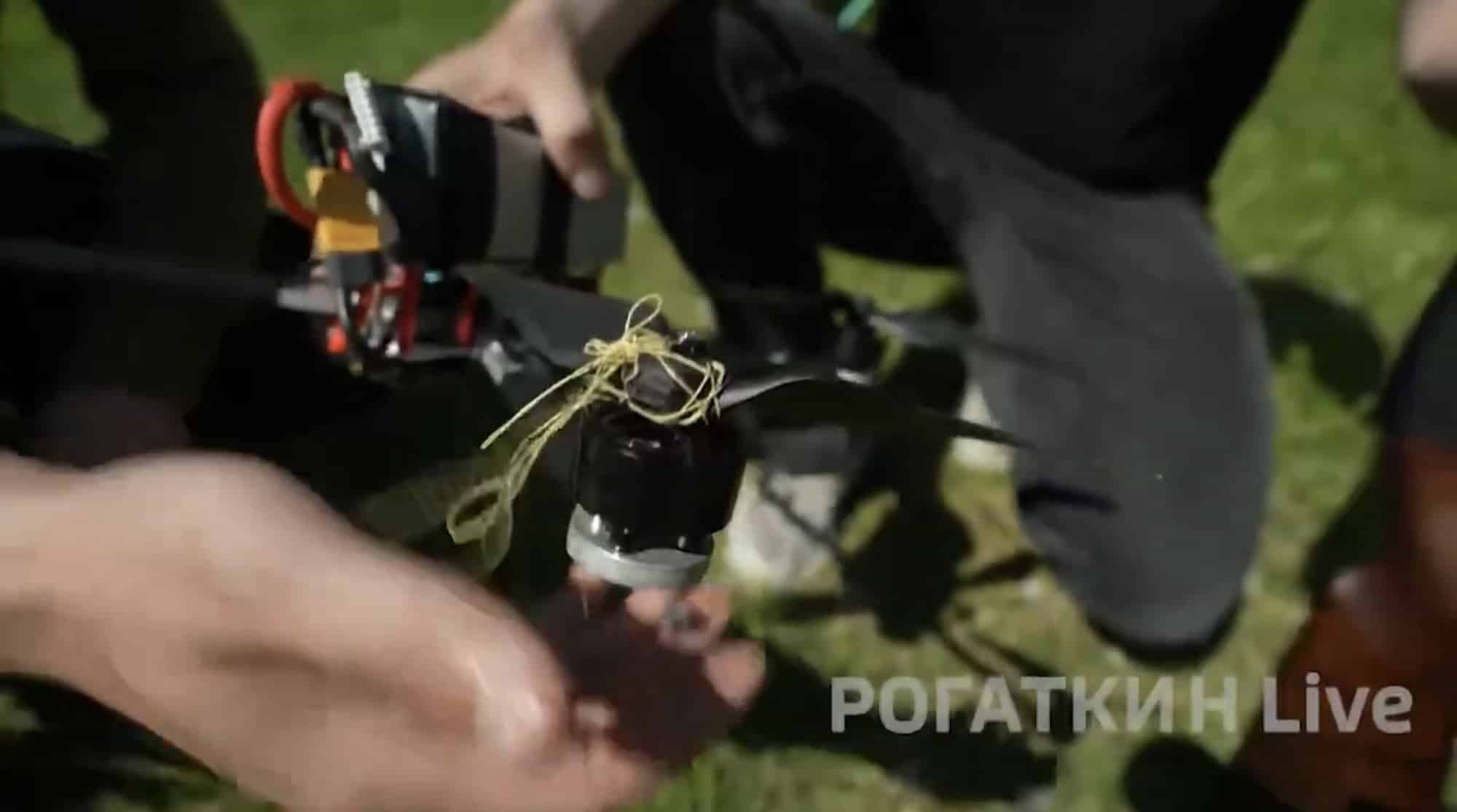 Hands holding a small quadcopter with net threads wound around its motor.