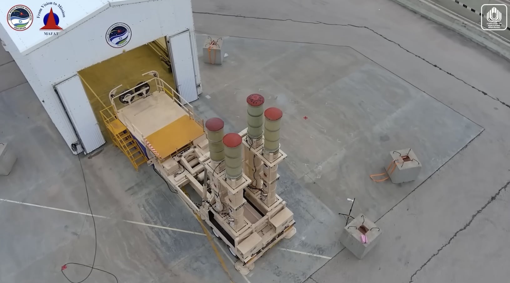 Overhead view of the launcher with capped interceptor canisters outside the open hangar.