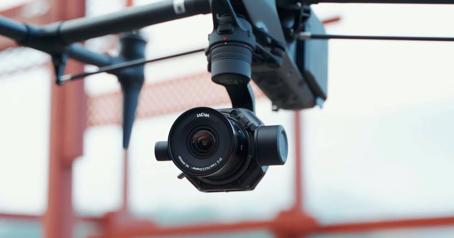 A Laowa DL lens mounted on a gimbal slung beneath a drone.