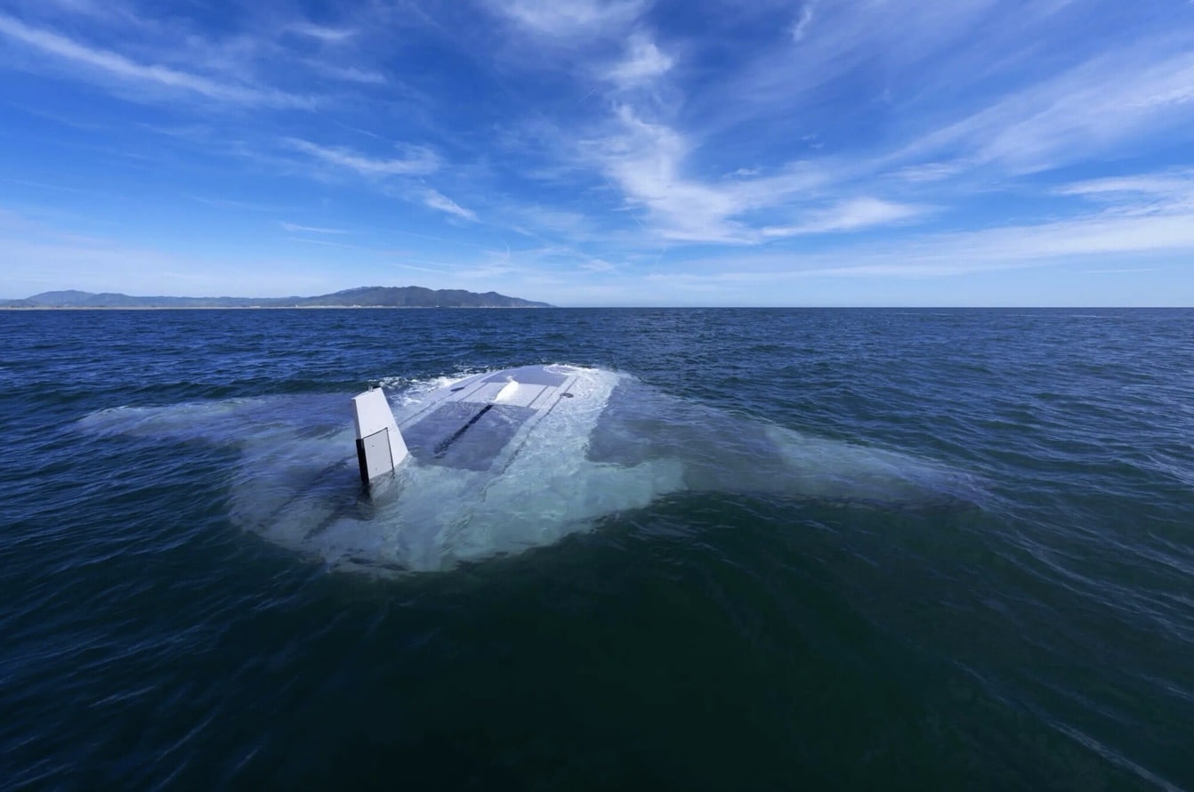 The Manta Ray uncrewed underwater vehicle awash offshore with an island on the horizon.