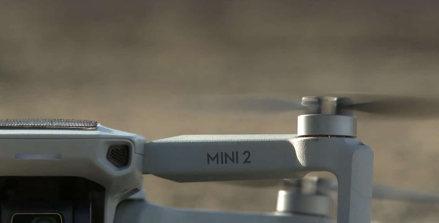 Close-up of a DJI Mini 2 hovering indoors with its motor arm in focus.