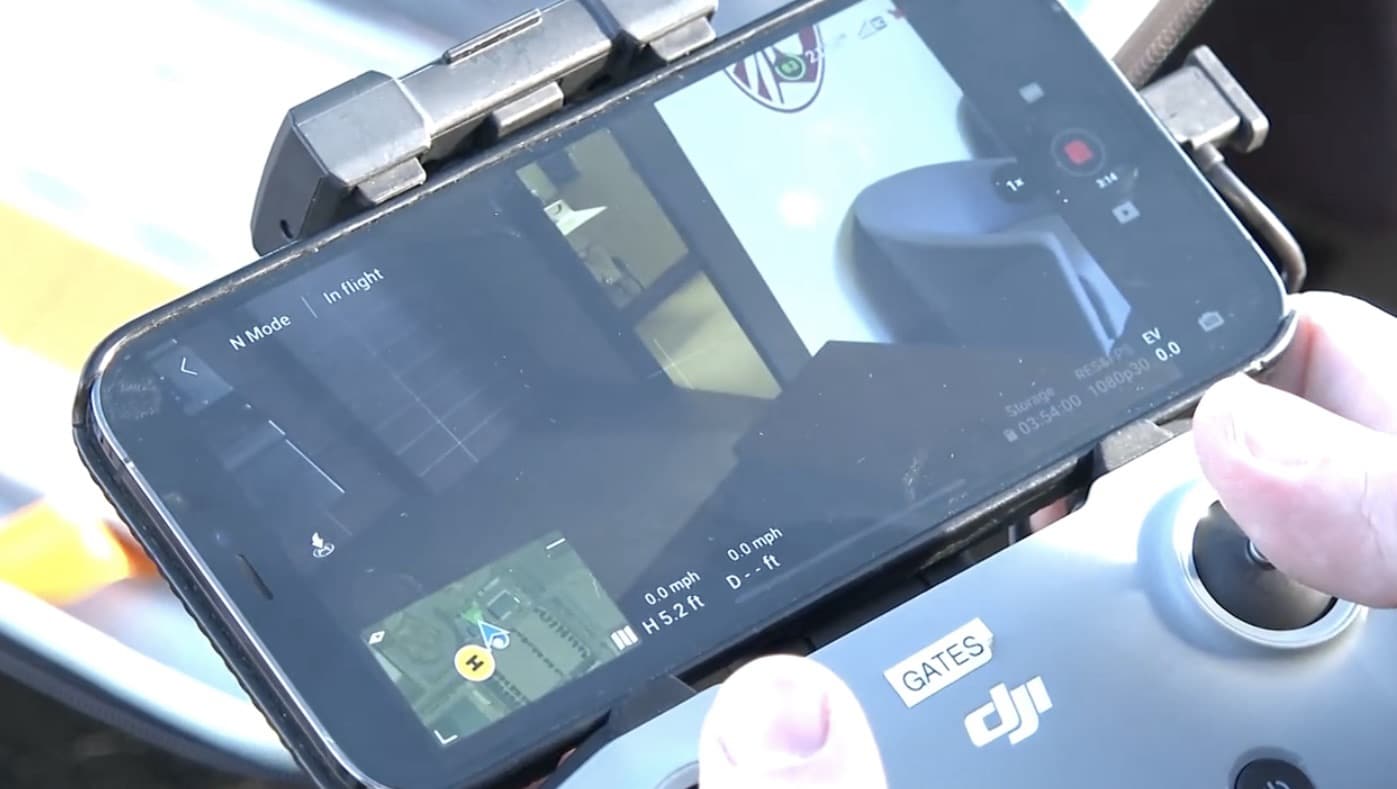 Deputy holding a DJI controller with a phone showing the live drone feed.