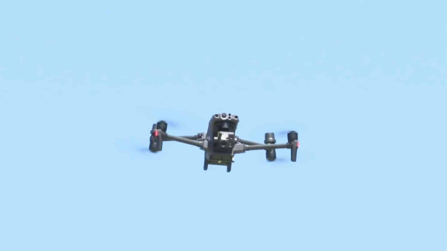 Public safety quadcopter with a zoom and thermal payload hovering against clear blue sky.