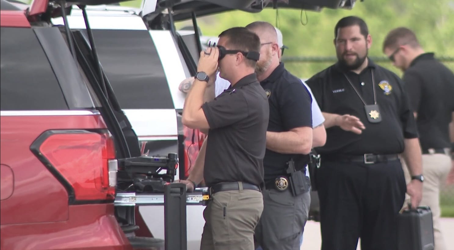 Trainees and a deputy gathered around a drone on a red pickup tailgate.