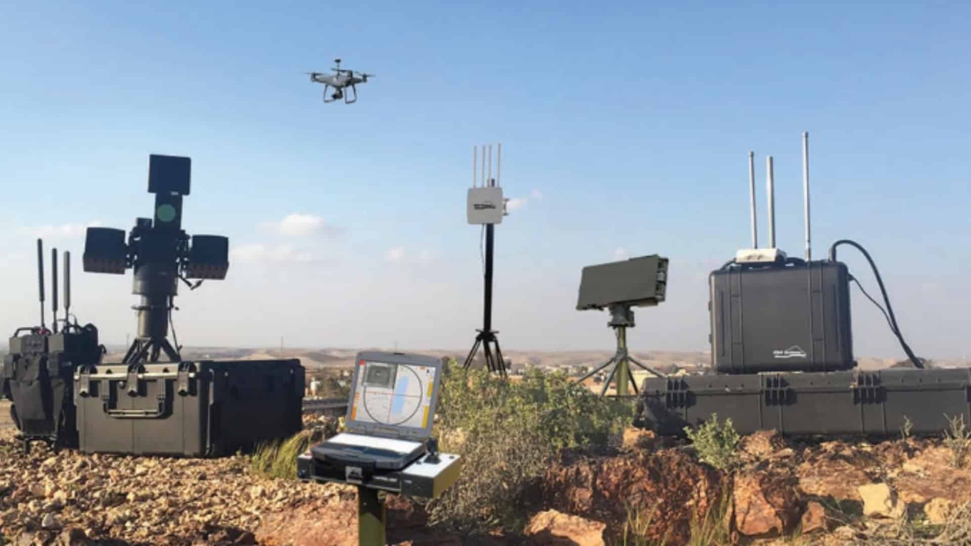 Counter-drone radar, jammers and optics deployed on desert ground as a quadcopter passes.