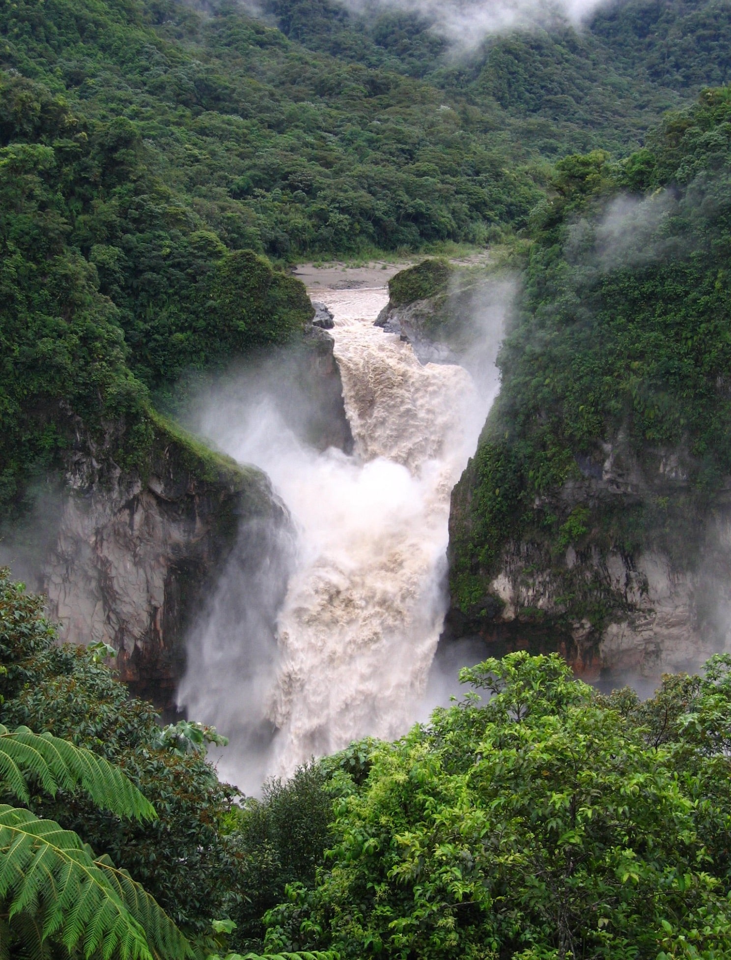 Coca River pouring through a mist-filled jungle gorge in the Ecuadorian Amazon.