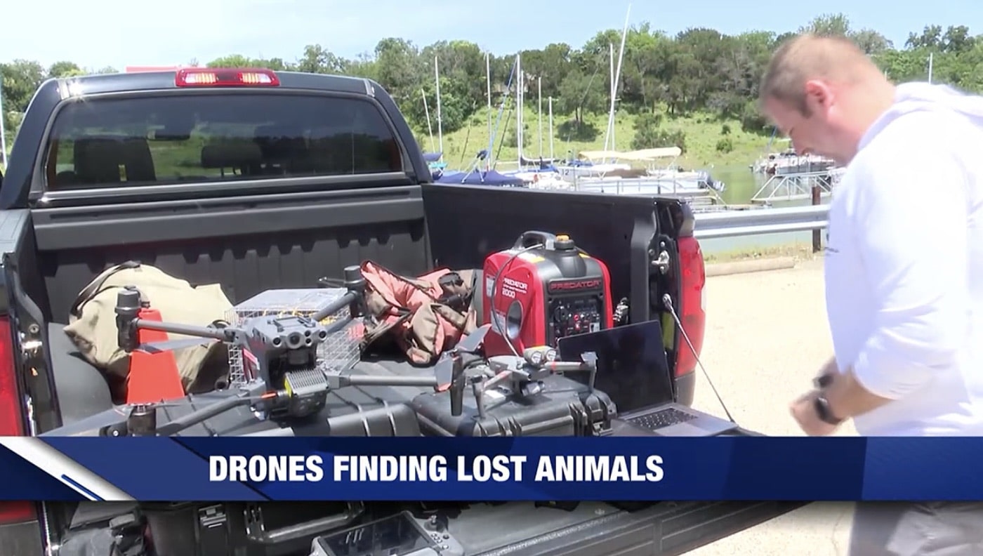 Operator loading drone cases and a generator into a pickup bed near a marina.