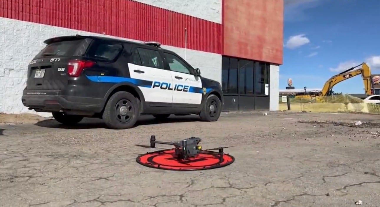 A drone waits on a red landing pad beside a Wheat Ridge police SUV.