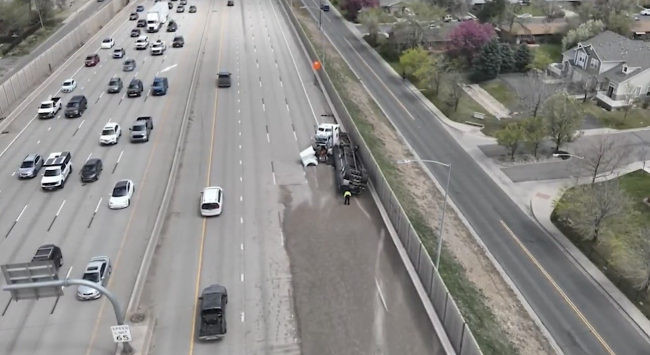 Aerial view of a crash scene on the shoulder of a busy highway.