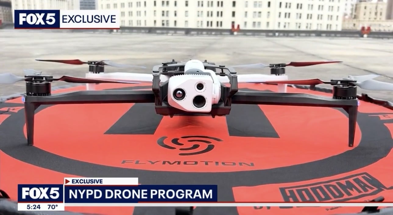 Screenshot of an NYPD quadcopter on a red landing pad on a rooftop.