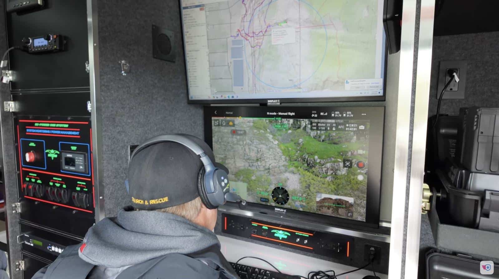 Operator in a headset watching mapping and video monitors inside the command van.