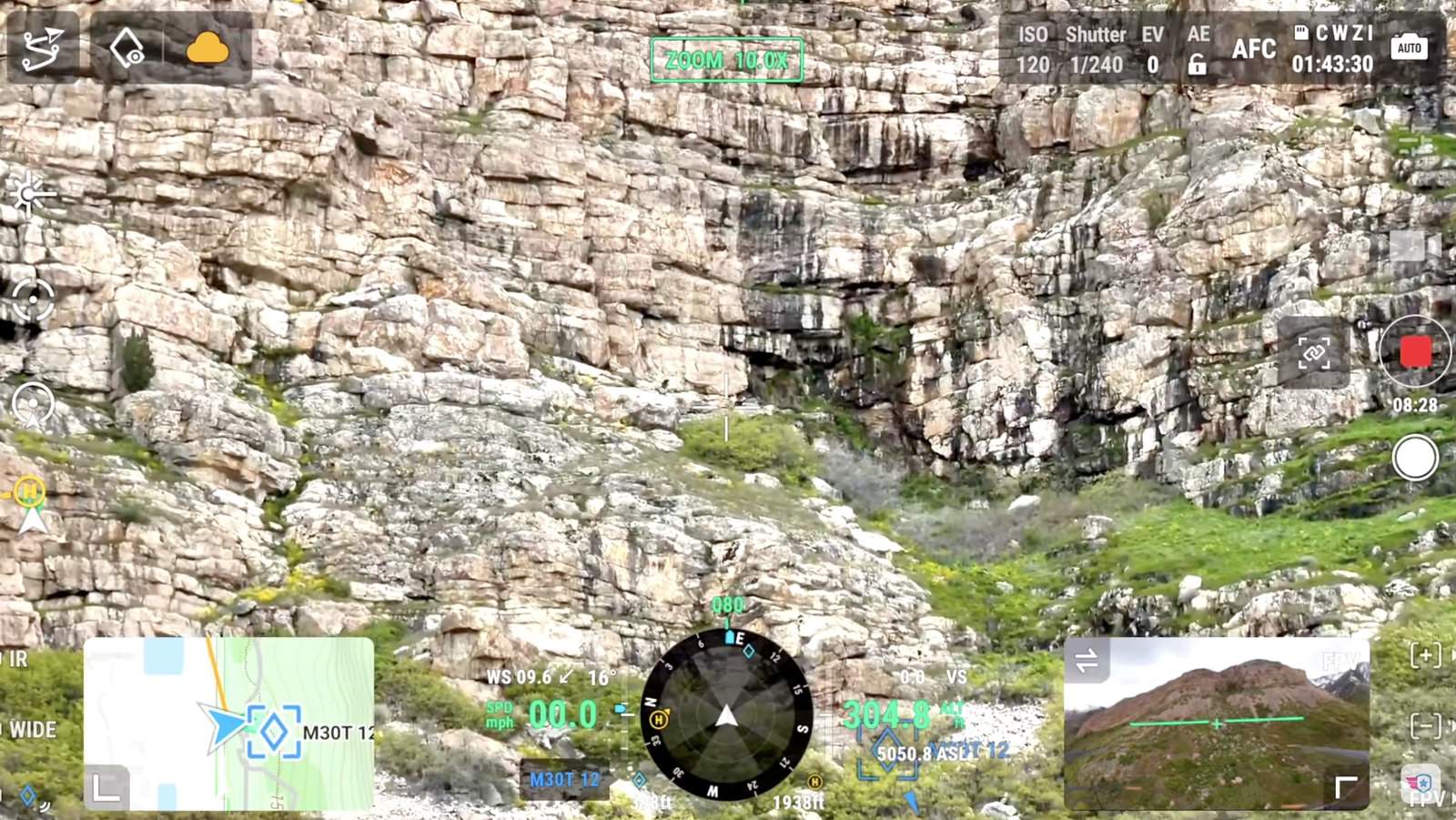 Drone camera view of a steep limestone cliff band with telemetry along the edges.
