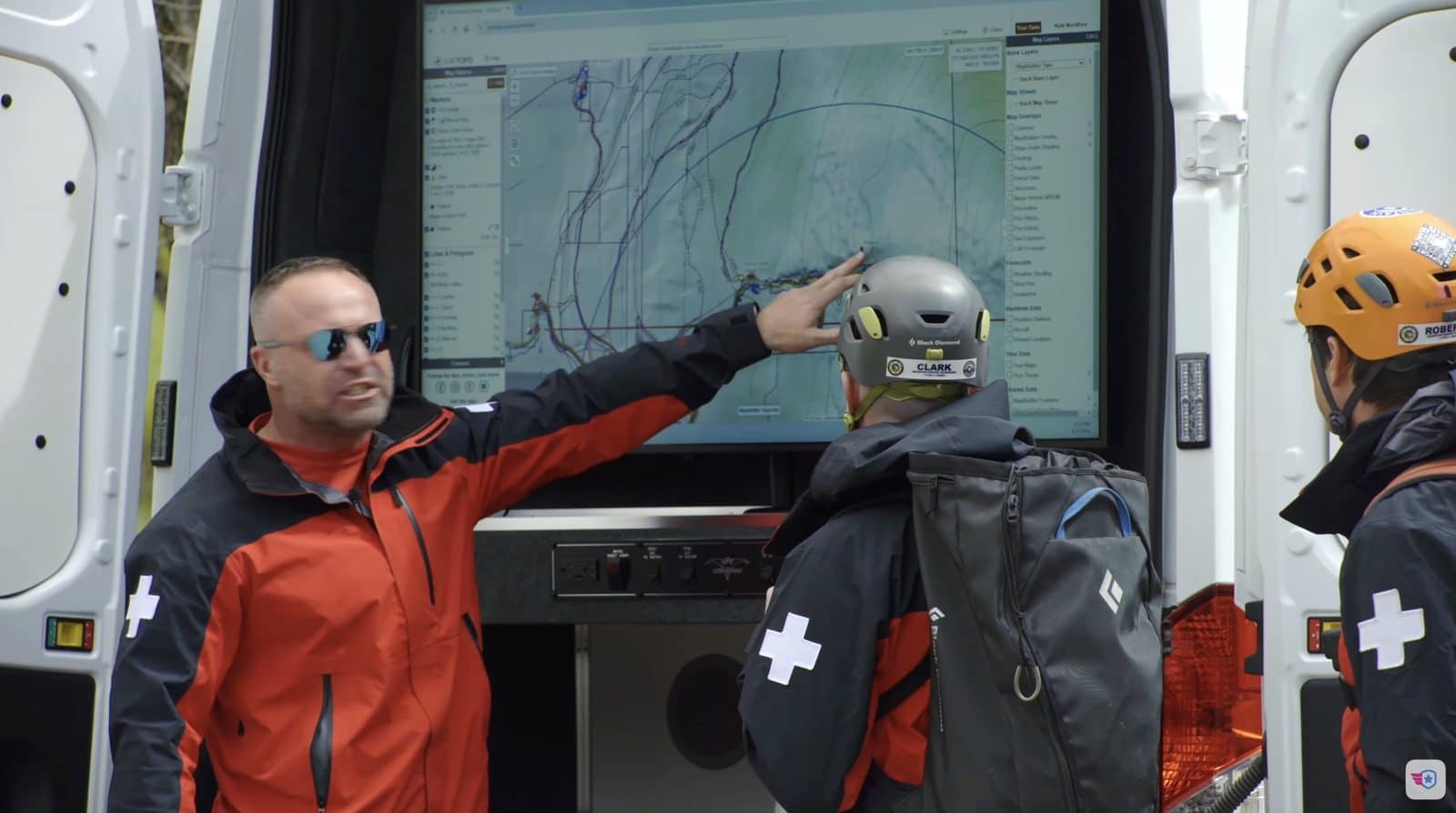 Incident commander pointing at the mapping screen while a rescuer studies the search area.