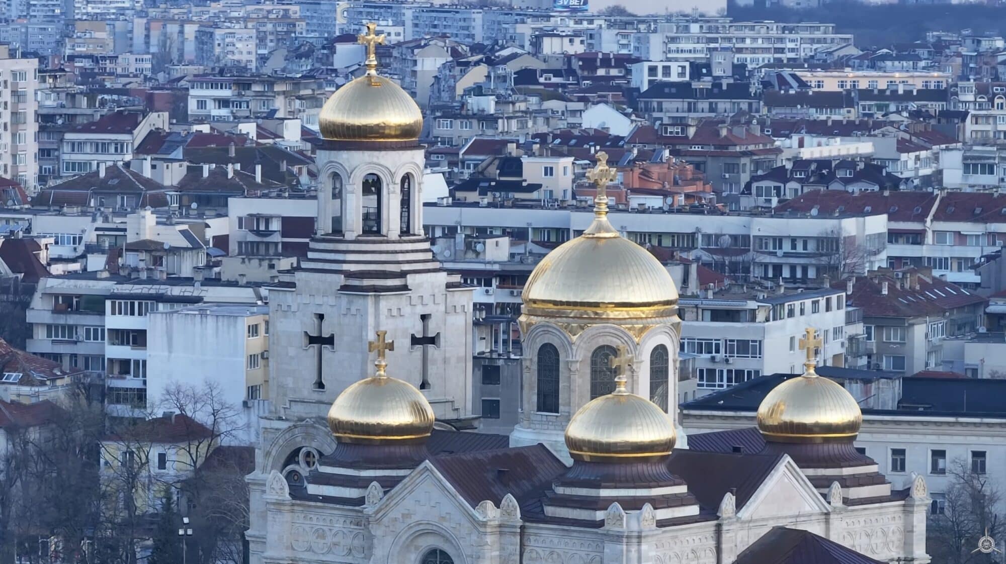 Golden-domed Orthodox cathedral rising above dense city rooftops from the air.