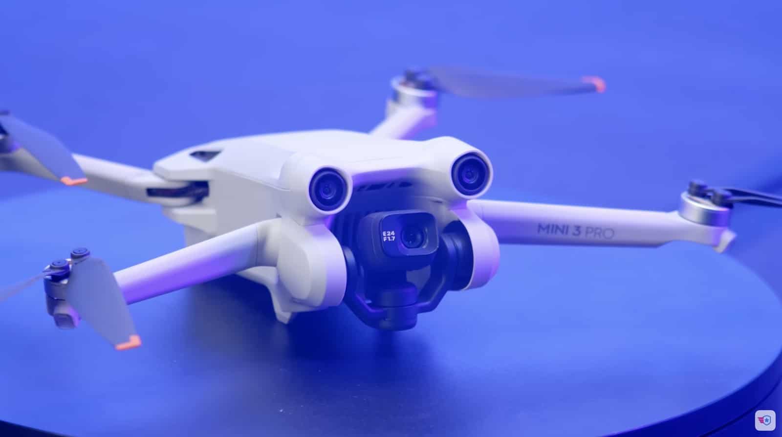 A DJI Mini 3 Pro turns on a blue display stand, arms unfolded.
