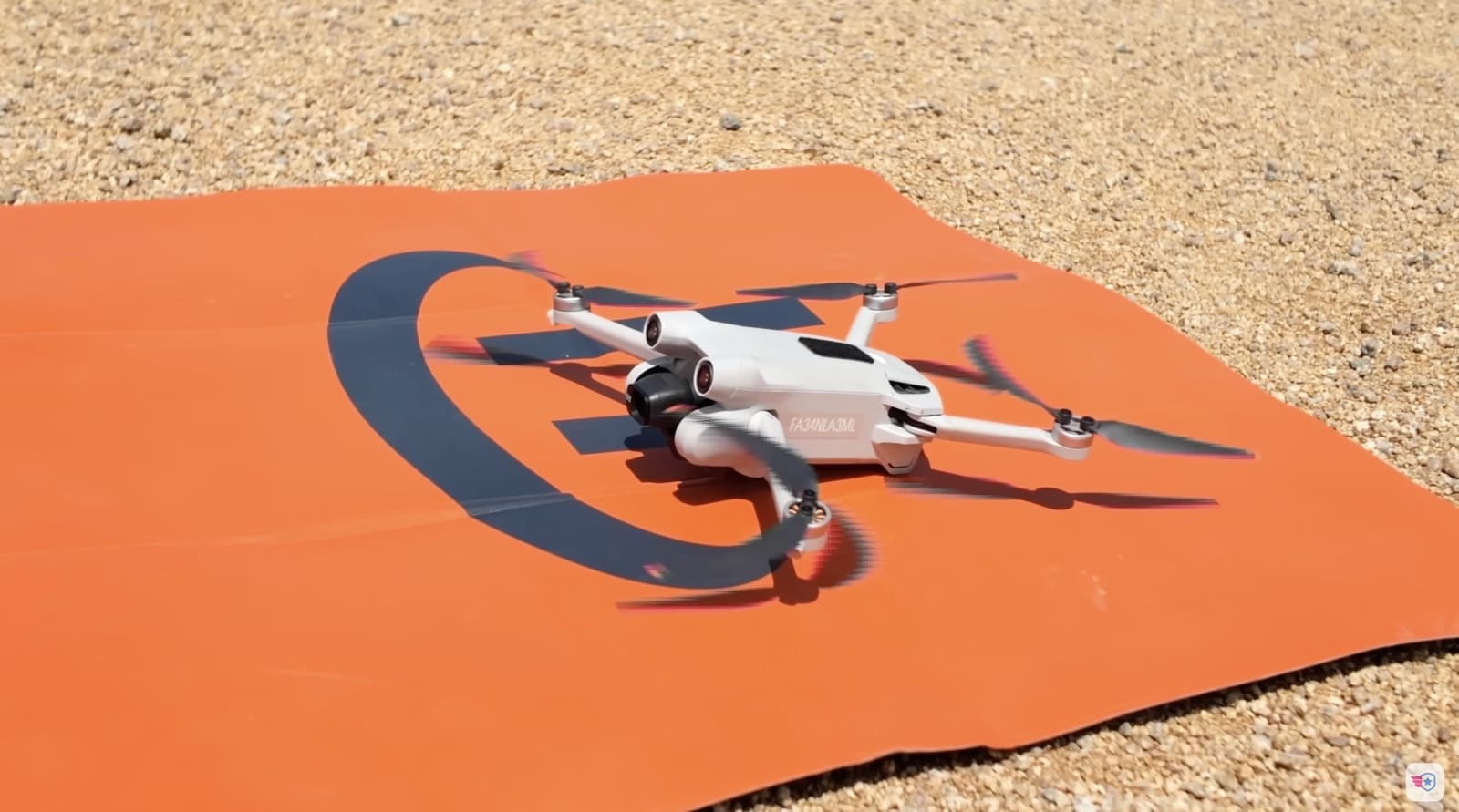 The Mini 3 Pro spins up on an orange landing pad in the dirt.
