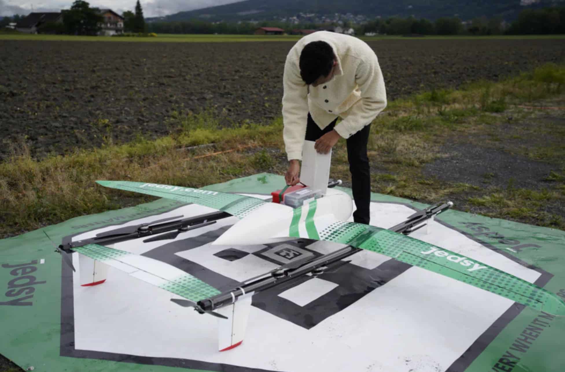 Operator loading a package into the Jedsy X parked on a marked landing mat.