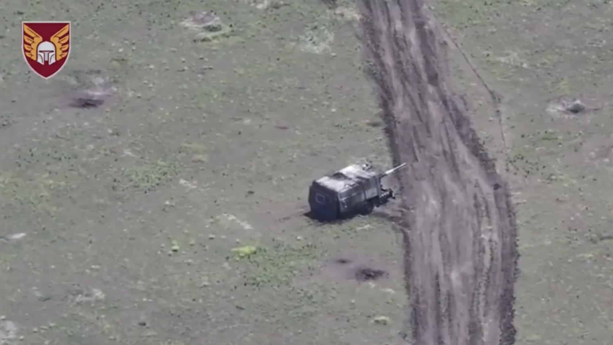 A Russian cage-armored turtle tank on a dirt track, seen from an FPV drone.