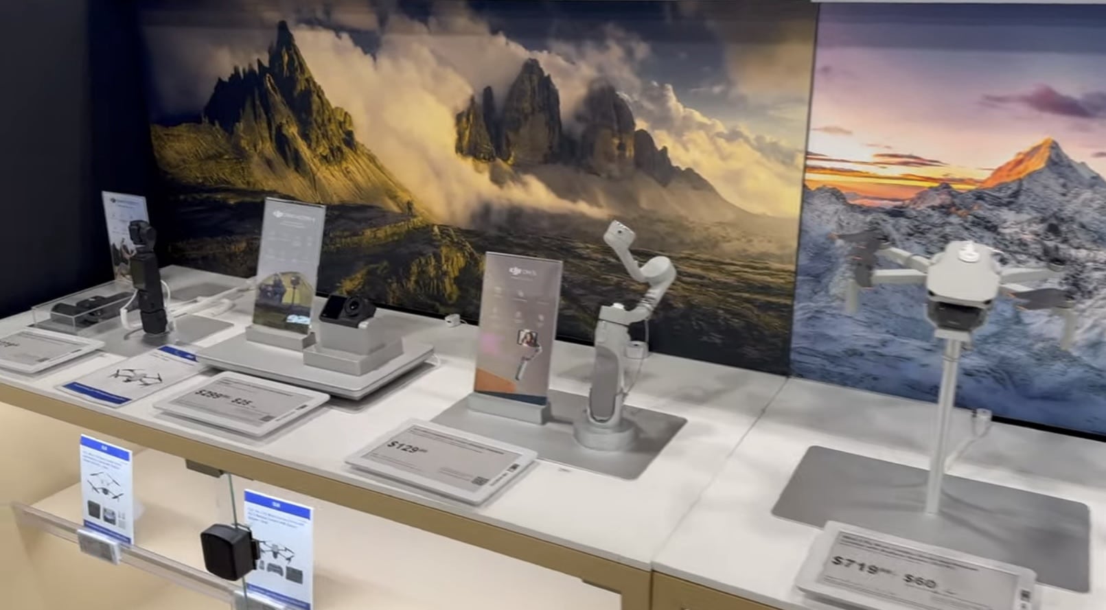 DJI gimbals, action cameras and a drone arranged on a Best Buy shelf.