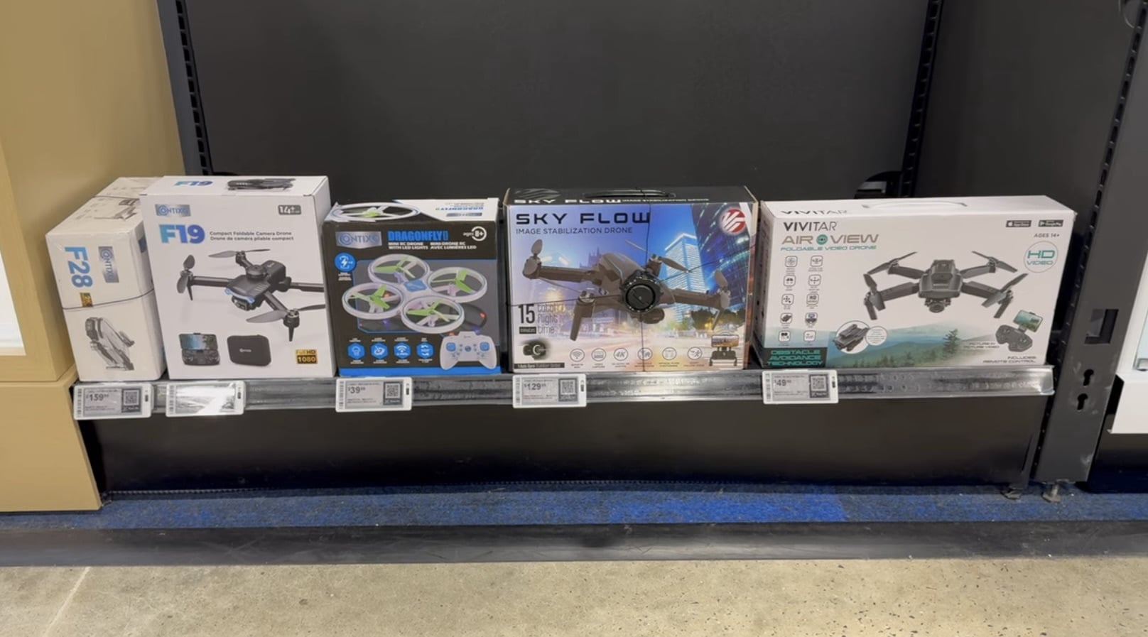 Boxed budget toy drones from F19, Sky Flow and Vivitar on a store shelf.
