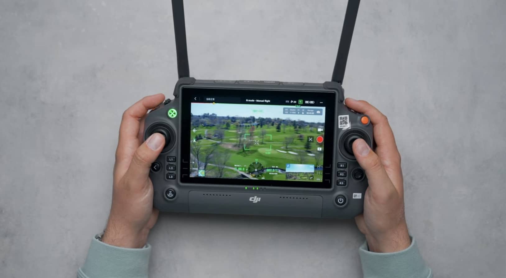 Hands holding a DJI RC Pro showing a live golf course camera feed.