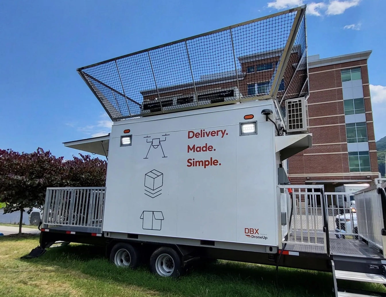 DroneUp delivery trailer with a launch platform parked outside a hospital building.