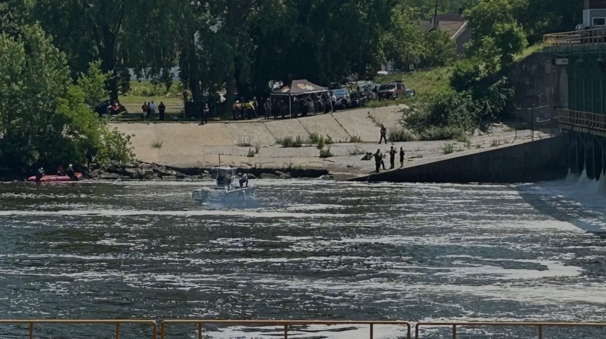 Rescue boat working the churning water below the Lock 12 dam as crews watch.